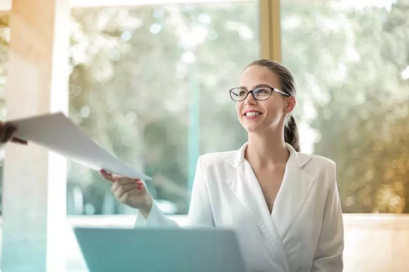 Une femme souriante tendant un document.